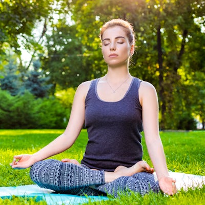 woman outdoors stretching meditating calming