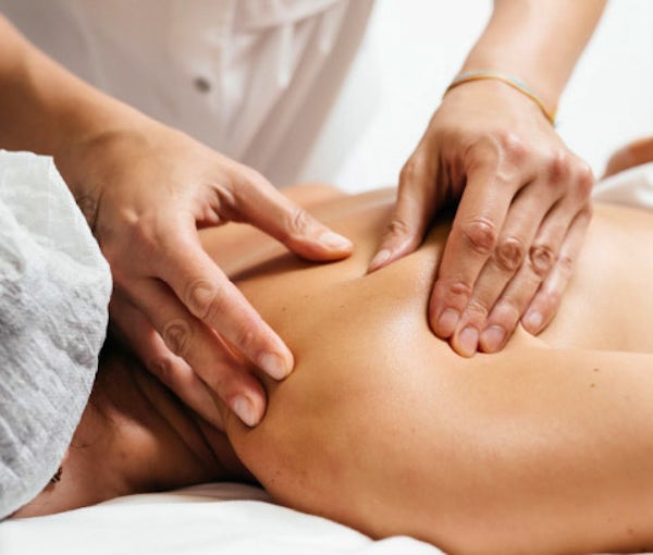  Massage therapist’s hands on patient’s shoulder