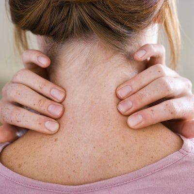 woman touches back of her neck with two hands
