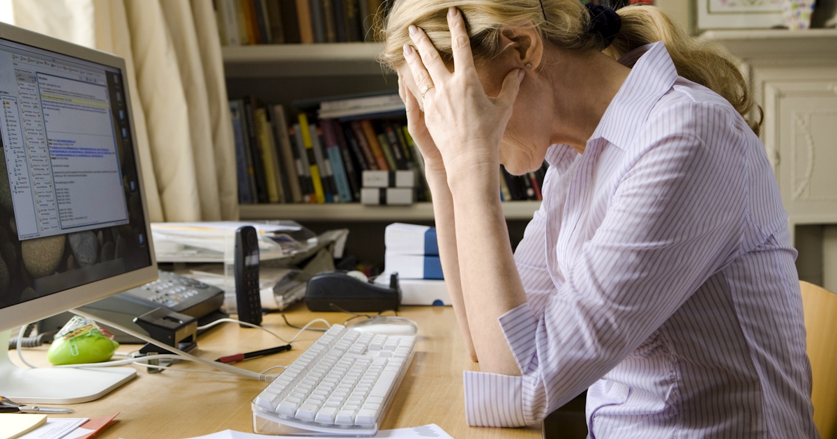 woman at computer holds head in her hands