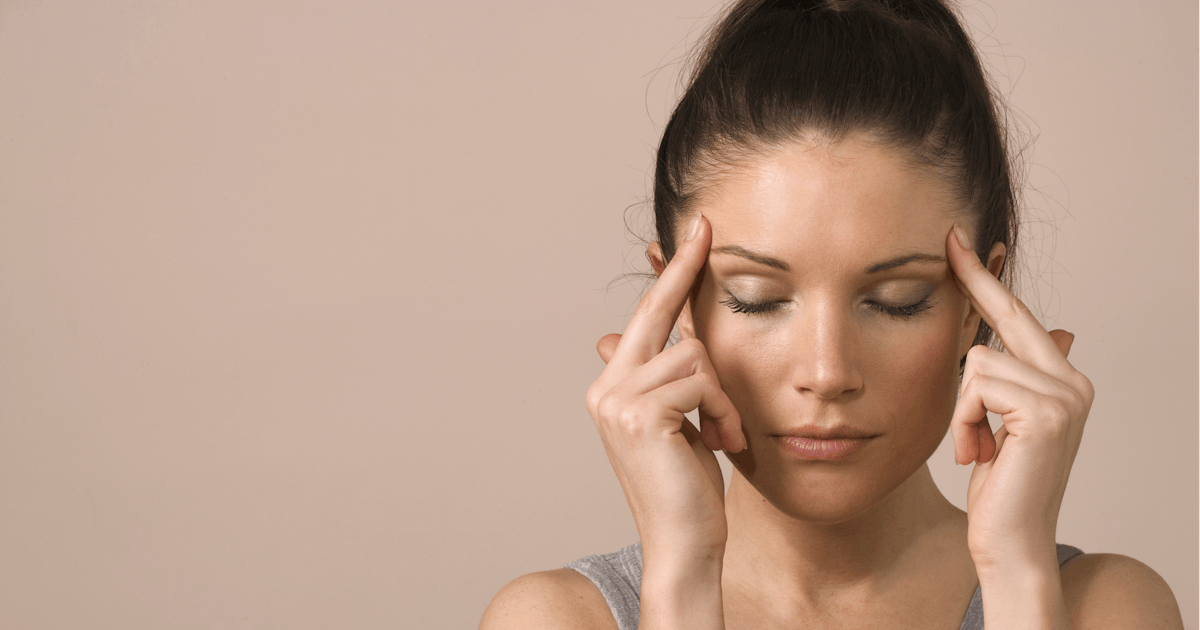 woman touches head with eyes shut