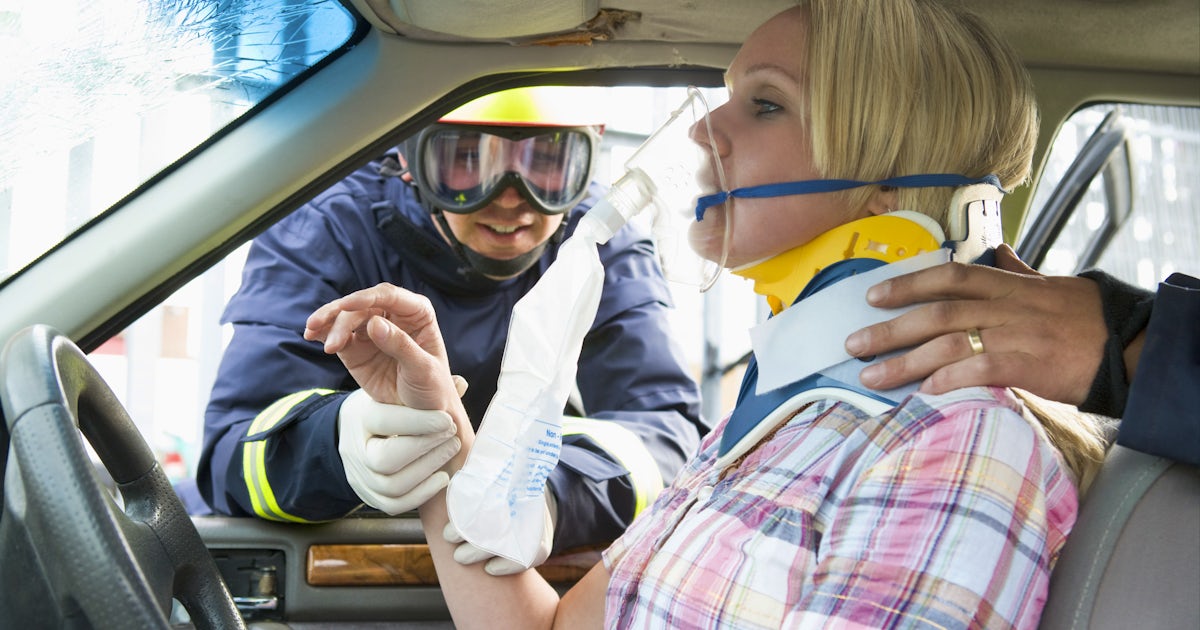 emergency responder gives oxygen and a neck brace to victim of car crash