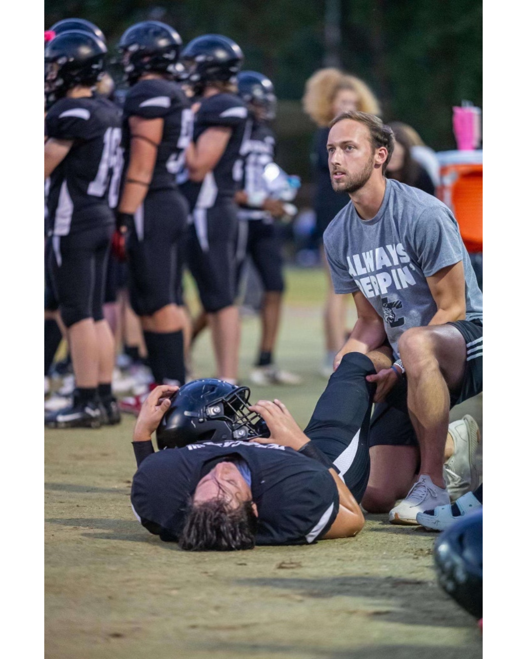 Dr. Hyde on the sideline of a football game performing chiropractic care on a player.