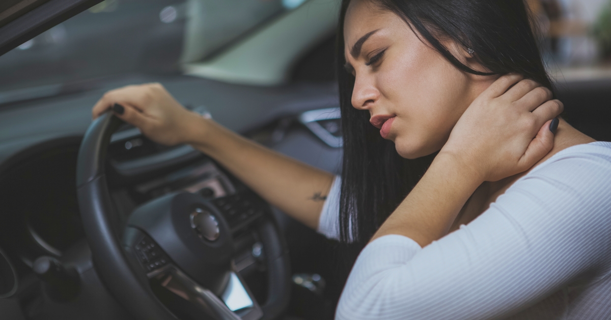 Female driver rubbing her aching neck after long d