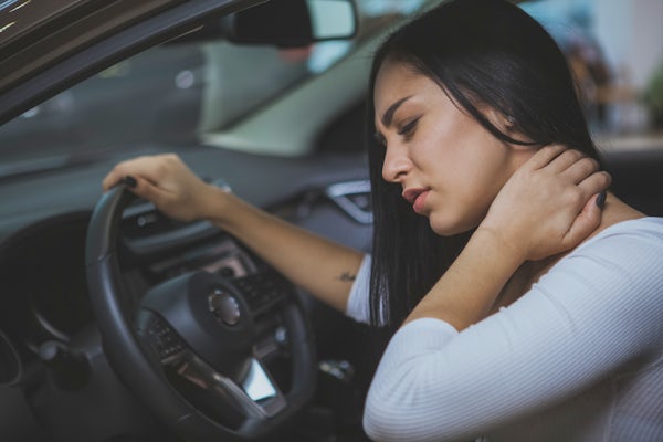 Female driver rubbing her aching neck after long d