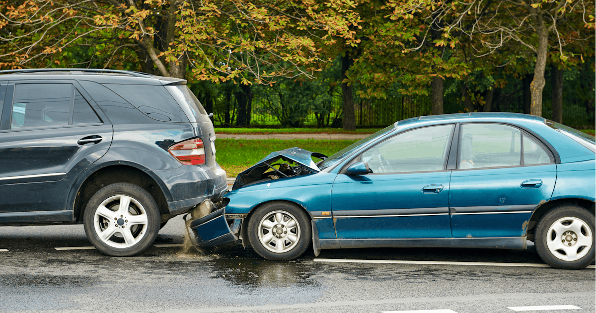 Two cars are involved in a collision on the roadside. One is a black SUV, and the other is a damaged blue sedan.