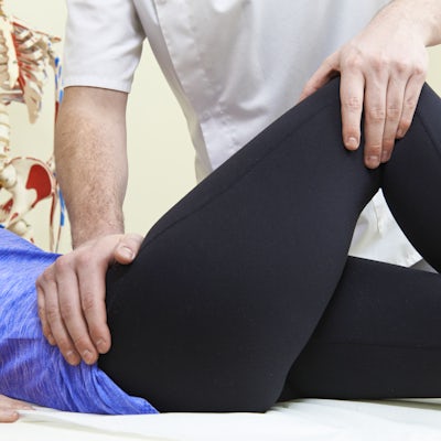 Male Osteopath Treating Female Patient With Hip Pr