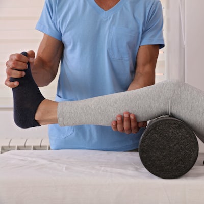 Therapist treating knee of athlete female patient