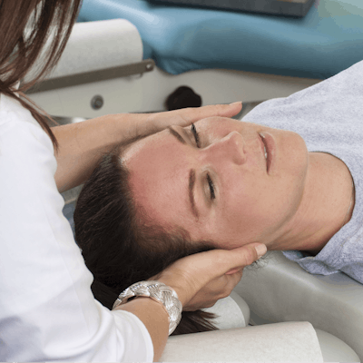Woman lying on table while chiropractor massages n
