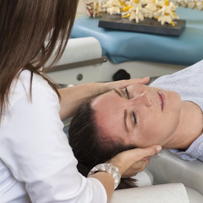 Woman lying on table while chiropractor massages n