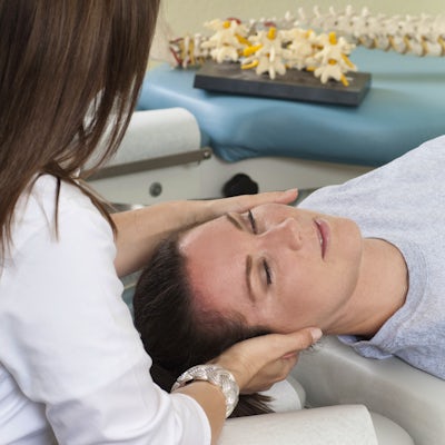 Woman lying on table while chiropractor massages n