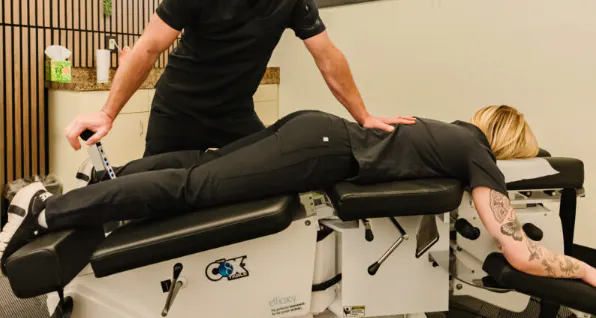 Chiropractor assessing and treating a patient lying face down for a lower back disc injury and related pain