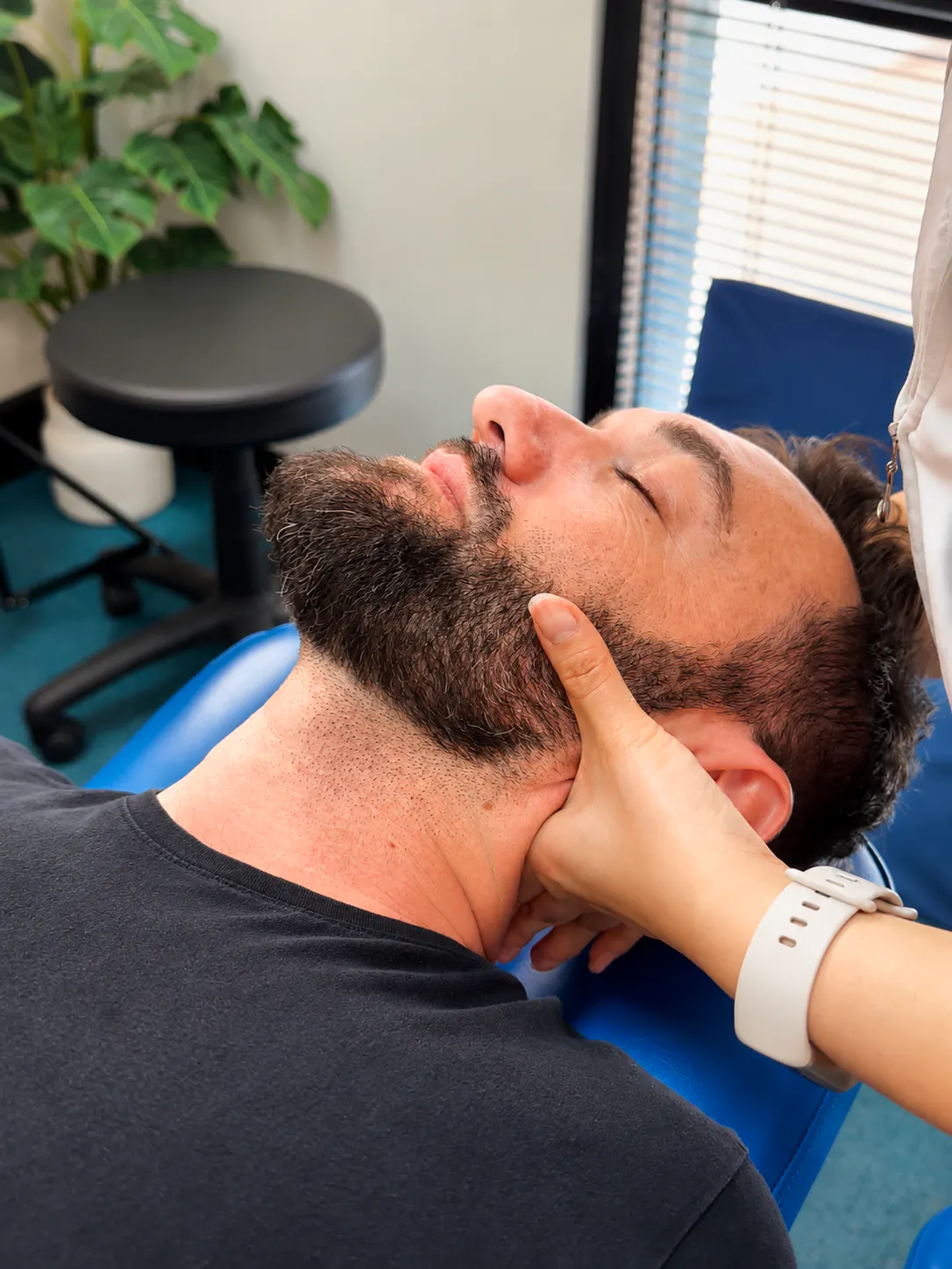 Chiropractor gently assessing a patient's jaw and neck for TMJ dysfunction and jaw pain in Joondalup
