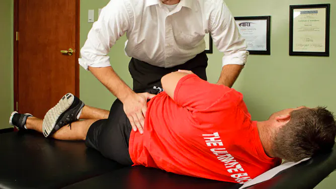 Chiropractor providing manual treatment to a patient with lumbar spinal stenosis and lower back pain