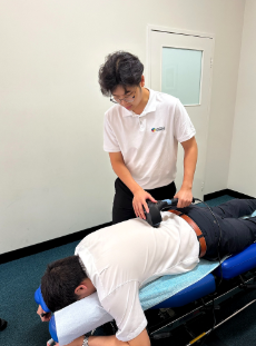 Chiropractor using a therapeutic device on a patient's lower back for mechanical low back pain treatment in Joondalup