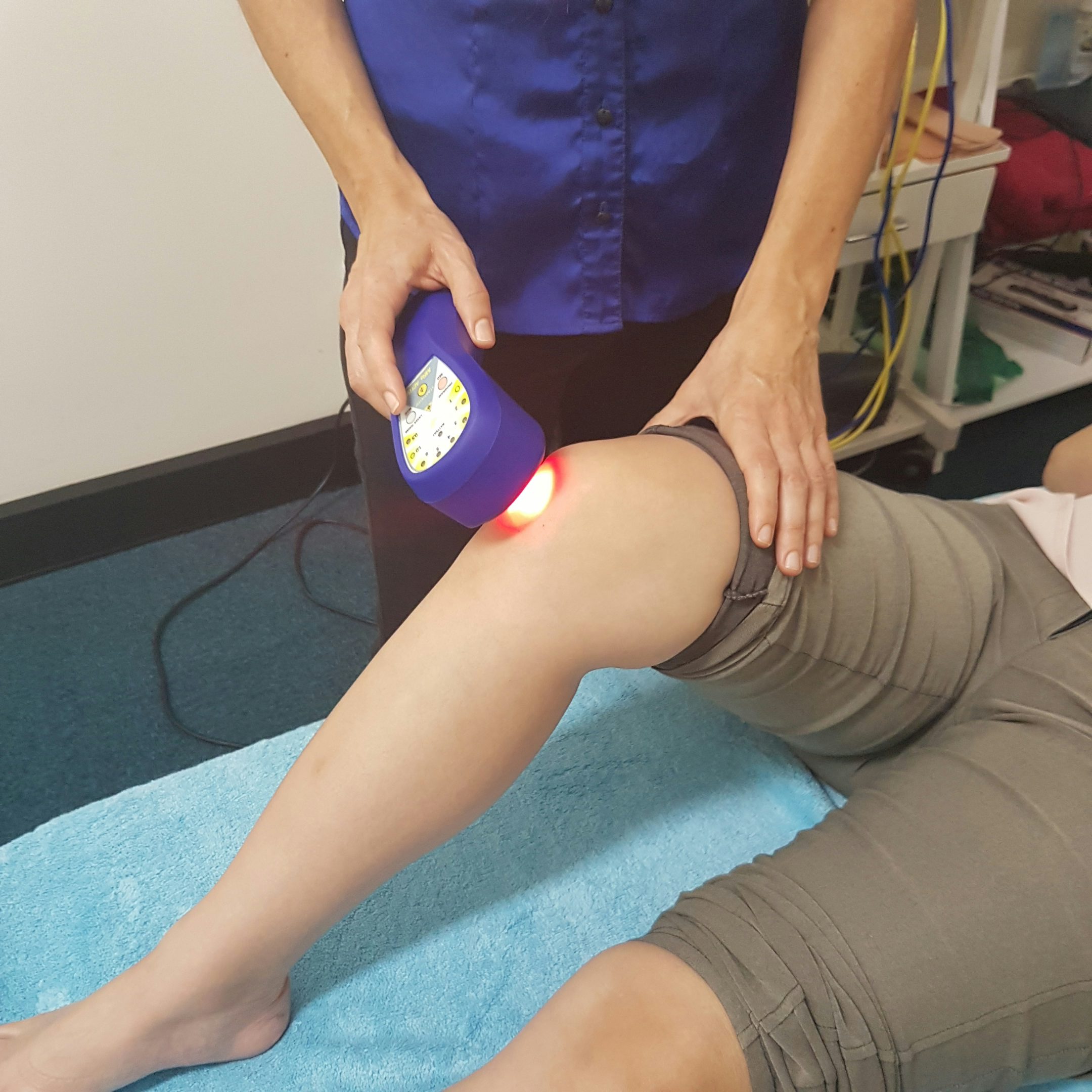 Chiropractor using cold laser therapy device on a patient’s knee to reduce inflammation and promote healing after a sprain.