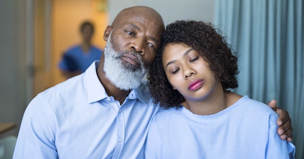 Sad father consoling ill daughter at hospital ward