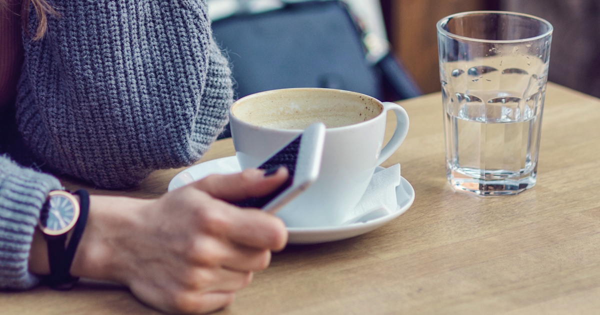 Woman sitting alone, having coffee and texting on