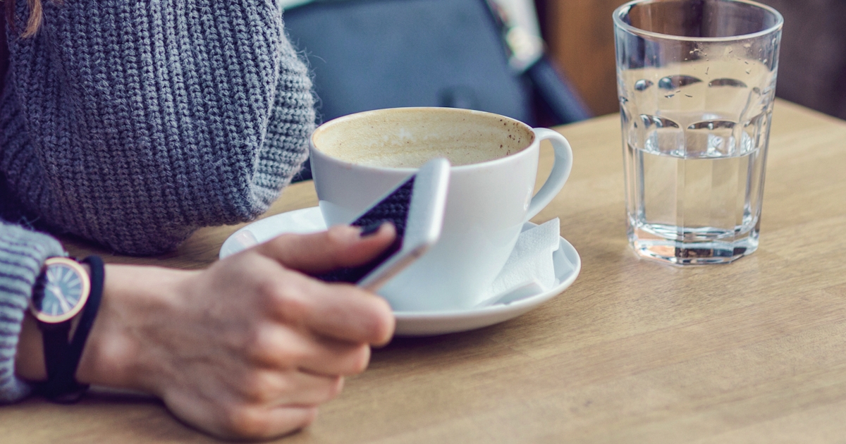 Woman sitting alone, having coffee and texting on 