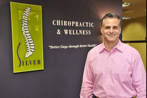 Dr. Silver smiling in front of practice's interior signage