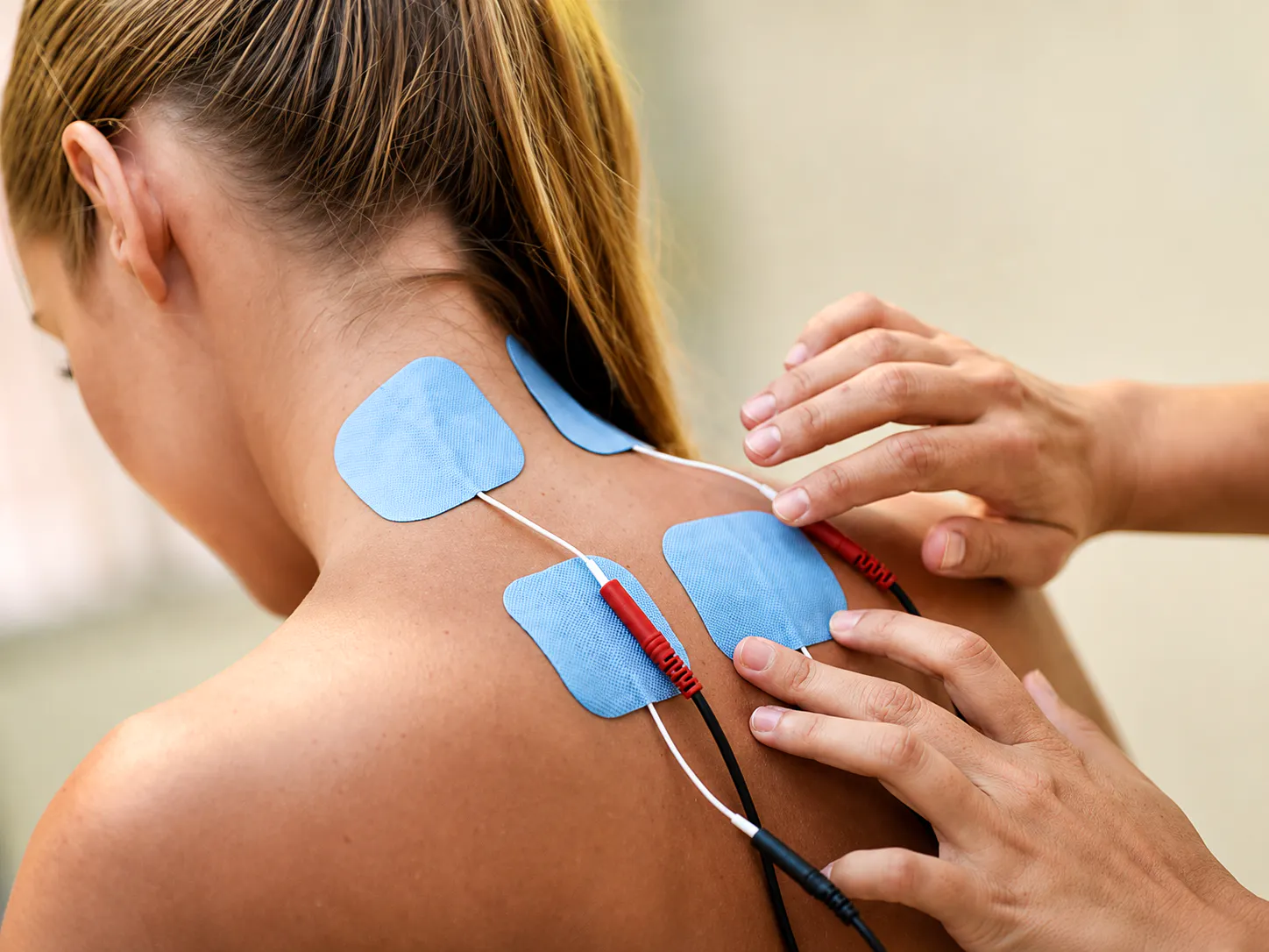 Electrotherapy pads placed on the upper back and neck for cervical facet pain and joint discomfort support