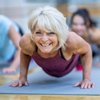 Senior Woman in Fitness Class in a Plank Pose Smil