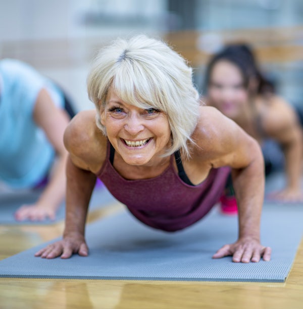 Senior Woman in Fitness Class in a Plank Pose Smil