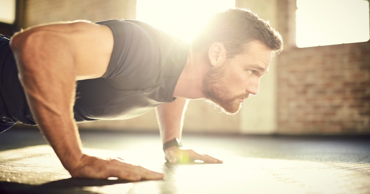 Side view of determined man doing push-ups in gym 