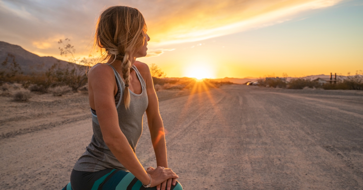 Young woman stretching body after jogging, sunset