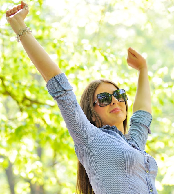 young attractive woman in park with arms up happy having fun sunny day