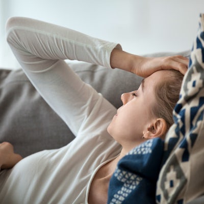 Upset depressed young woman lying on couch feeling