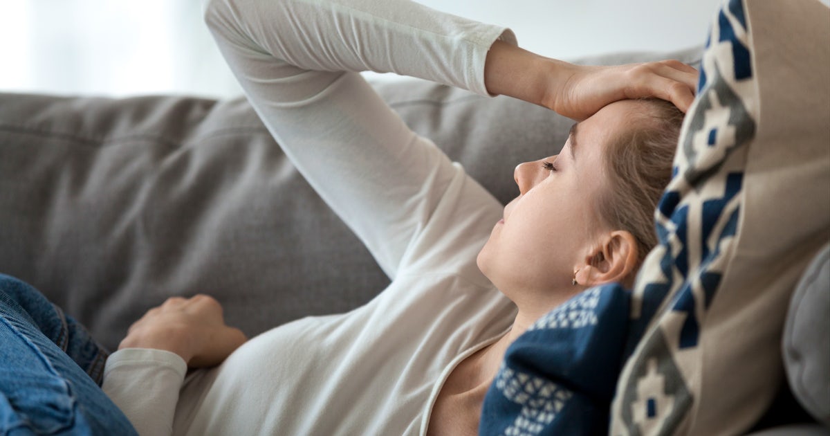 Upset depressed young woman lying on couch feeling