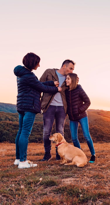 Family with dog embracing while standing on the hi