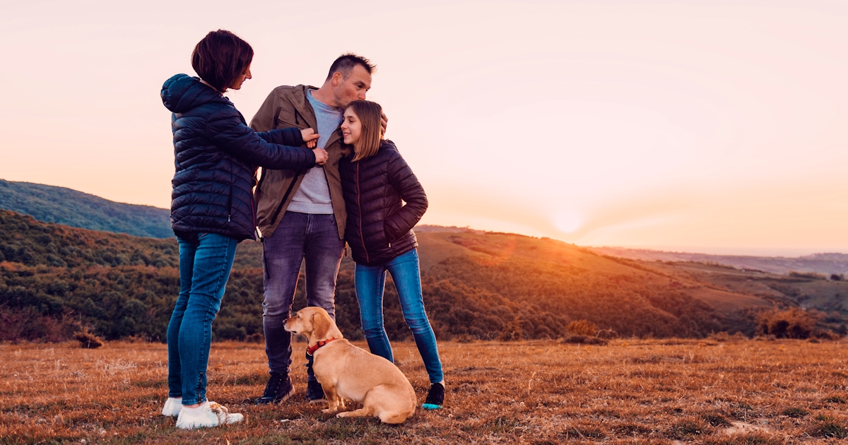 Family with dog embracing while standing on the hi