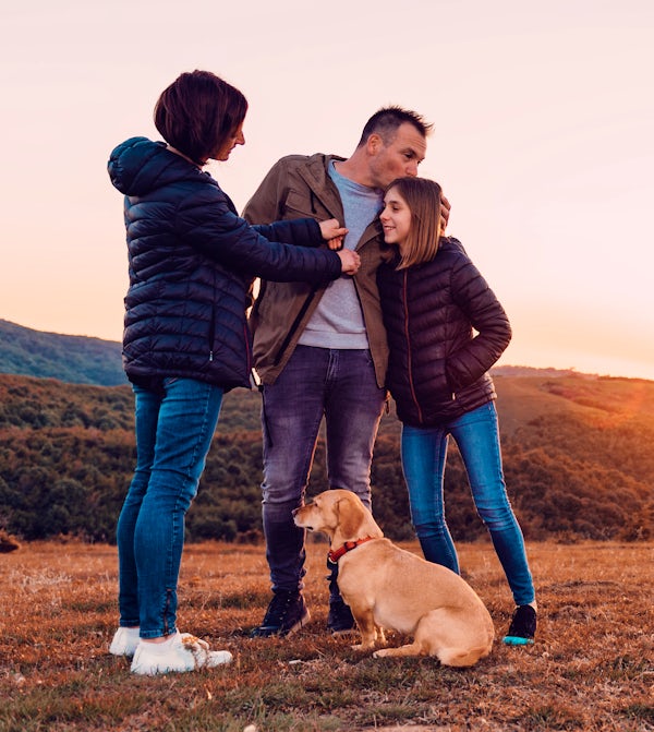 Family with dog embracing while standing on the hi