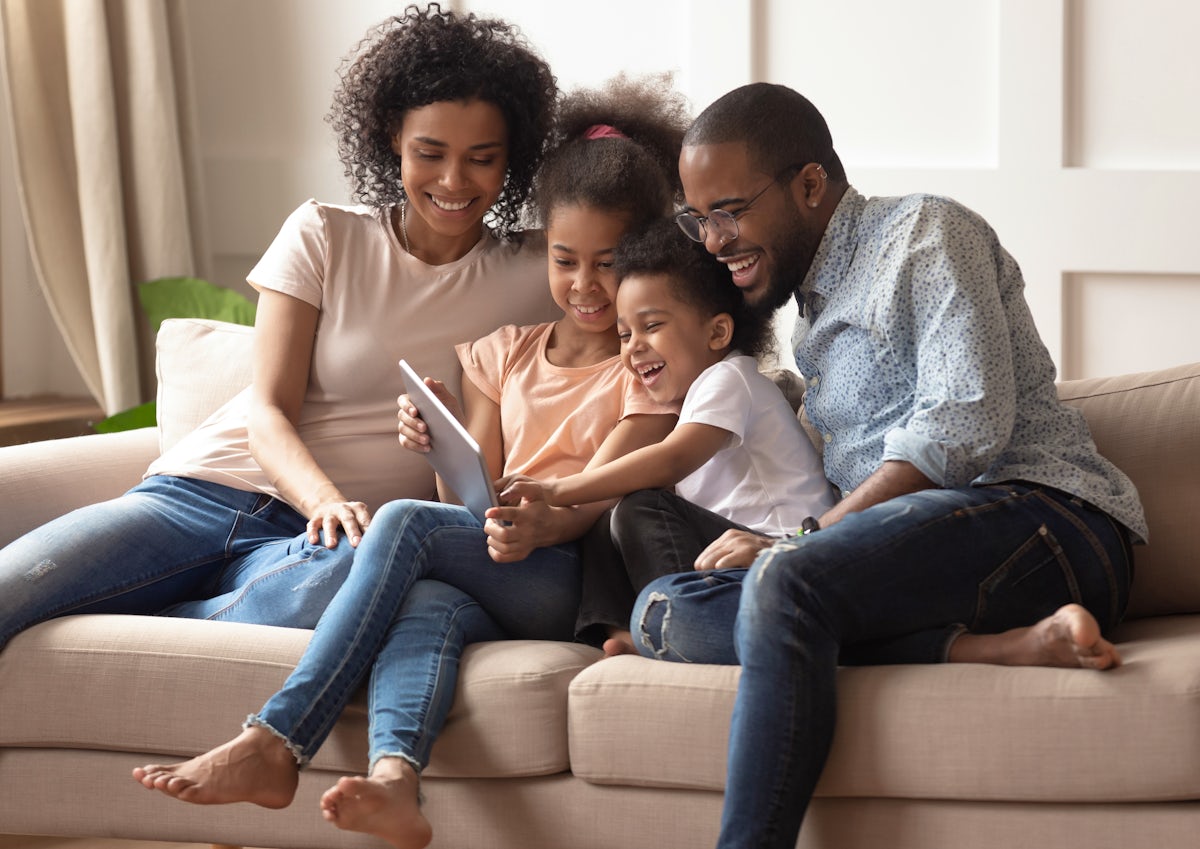 Happy black parents and children using digital tab