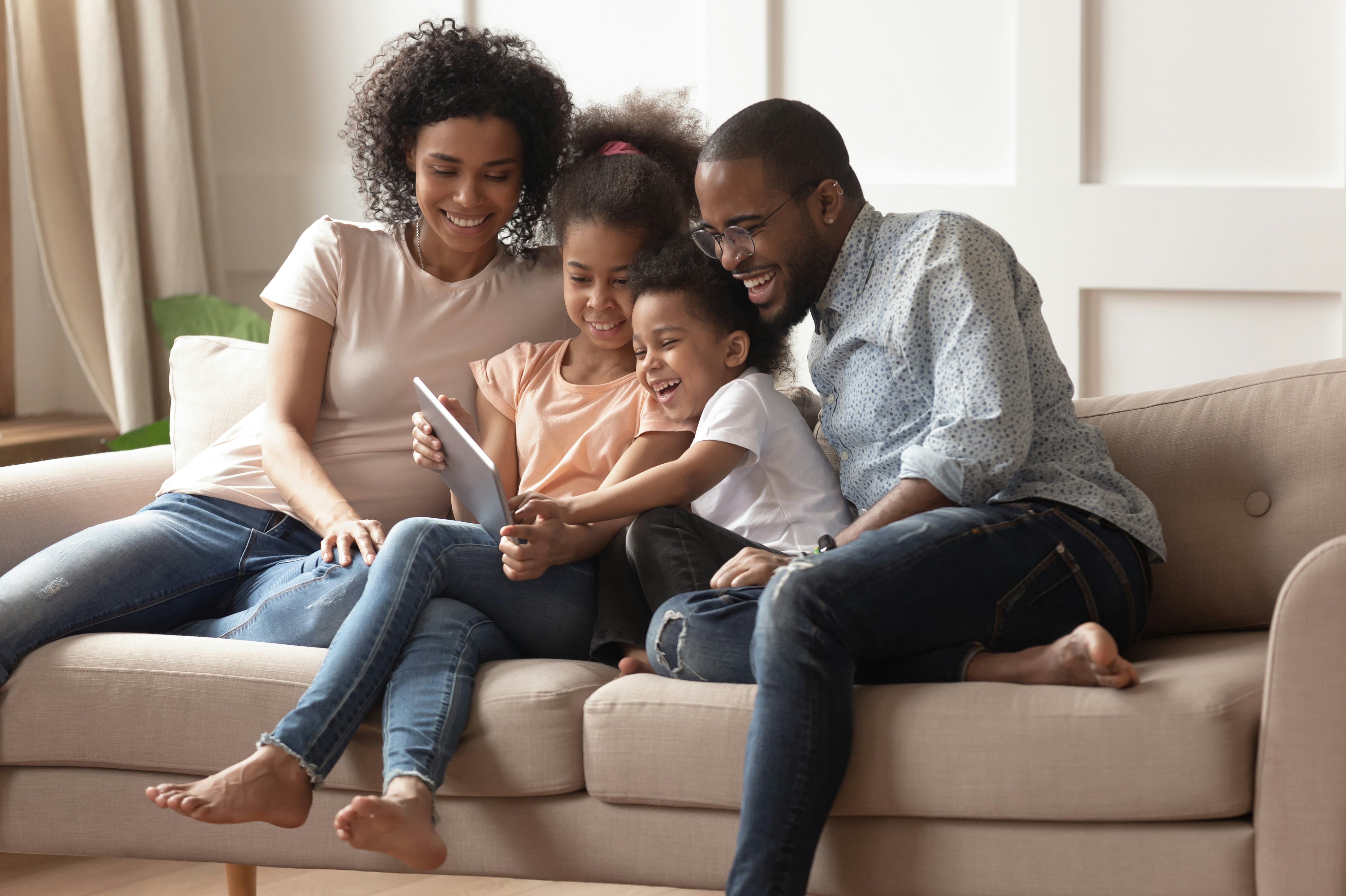 Happy black parents and children using digital tablet