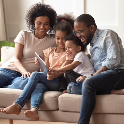 Happy black parents and children using digital tab