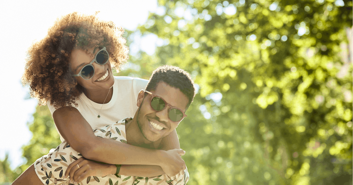 Young couple enjoying piggyback ride on sunny day
