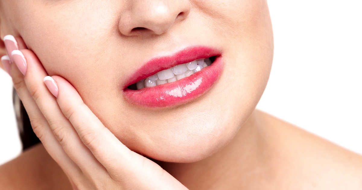The image shows a close-up of a woman with glossy lips, holding her face with one hand, possibly expressing discomfort or concern.