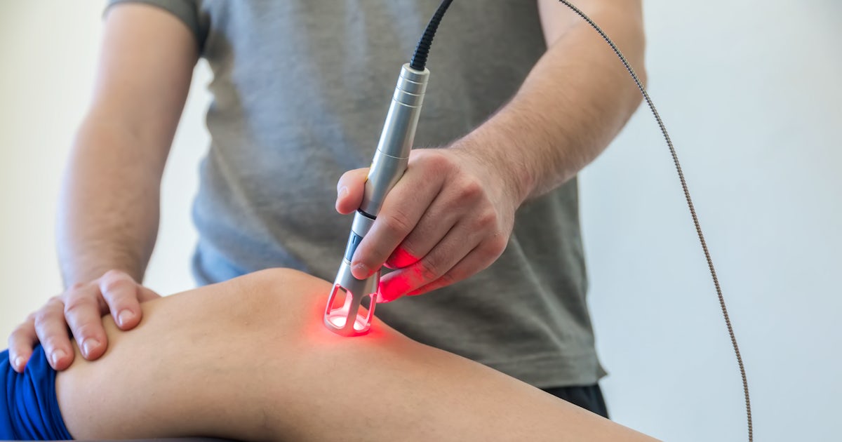 up close white male leg laser therapy on knee glowing red male chiropractor doctor