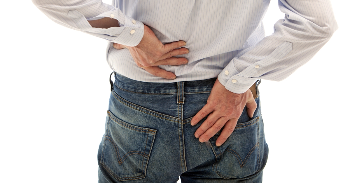 clothed back of middle half of white man with both hands on lower back pain