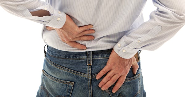 clothed back of middle half of white man with both hands on lower back pain