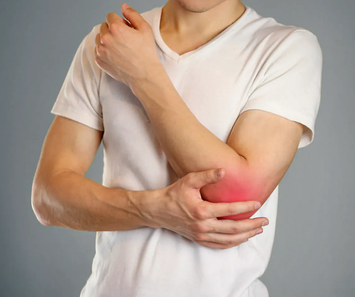 Man holding his elbow with tennis elbow pain and lateral elbow discomfort