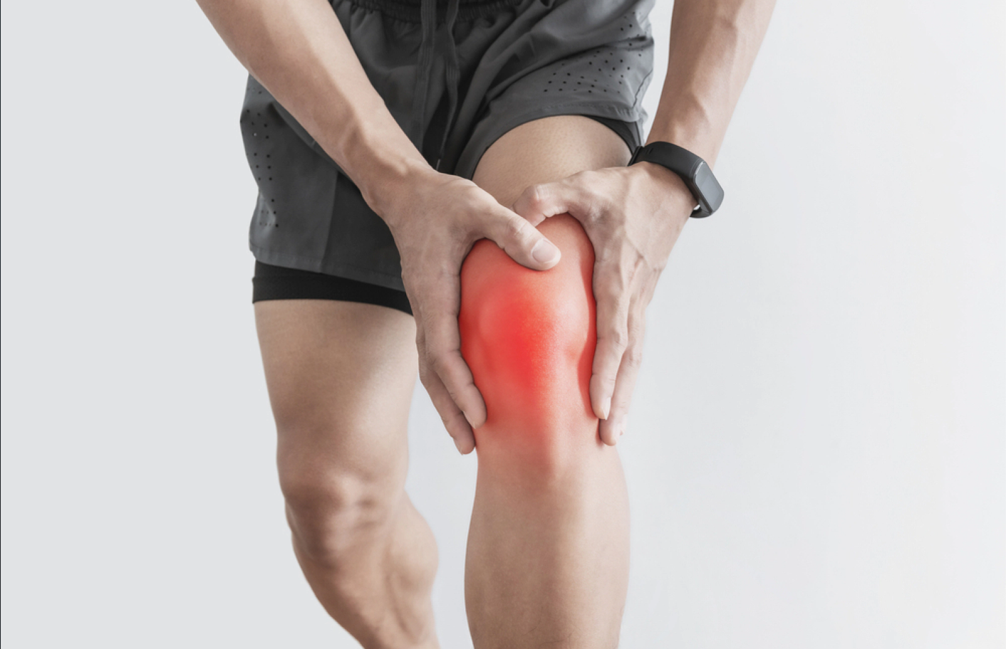 Man holding his knee with visible swelling and redness, showing pain from a knee sprain injury.