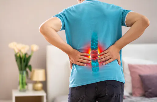 Man holding his lower back with a highlighted lumbar spine showing pain and inflammation from a disc injury