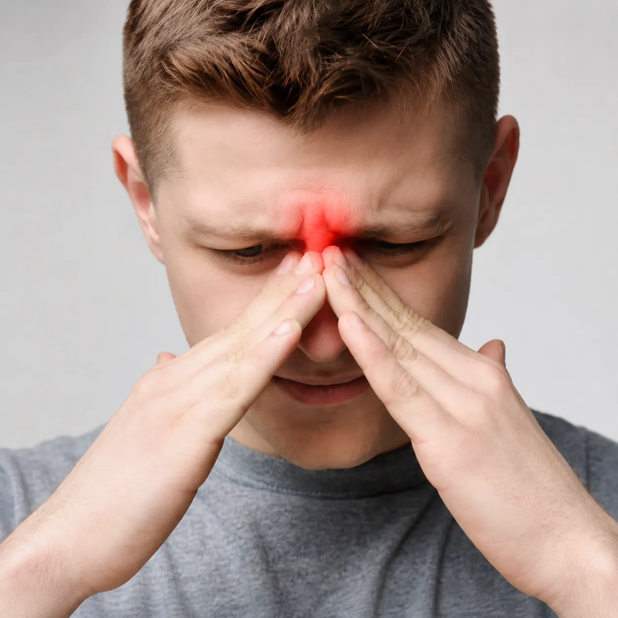 Man pressing the bridge of his nose with sinus pressure and sinusitis discomfort