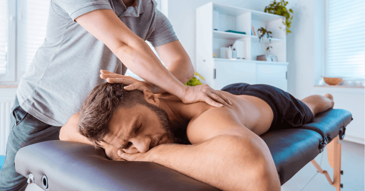 Massage therapist massaging back of the young man