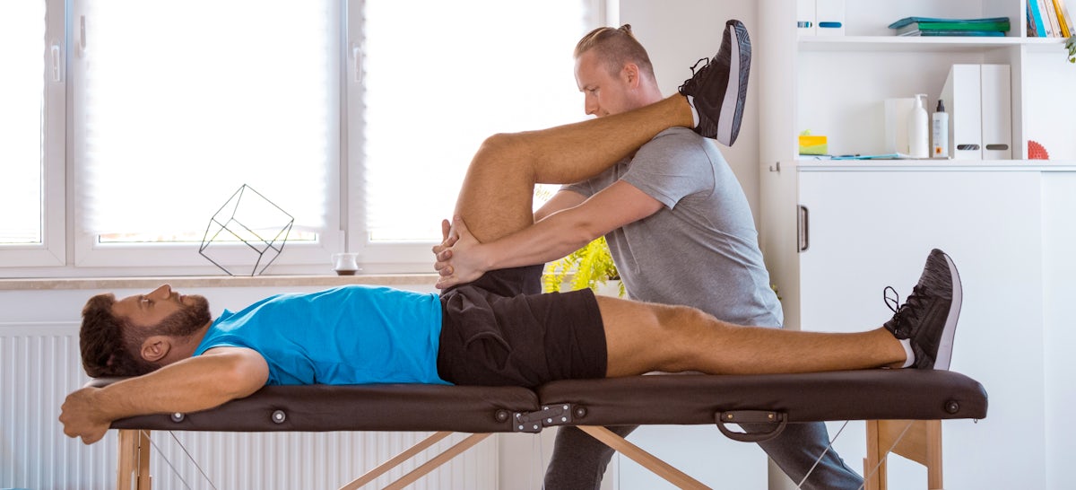 Physical therapist examining young man in rehabili