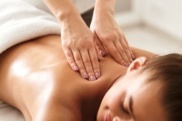 Young woman enjoying therapeutic neck massage in s